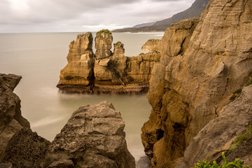 Fototapeta na wymiar Rock sea stacks near the Pancake Rocks, Punakaiki, New Zealand at sunset using long exposure.