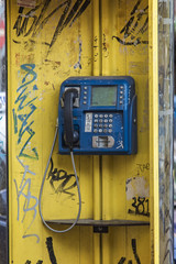 Fototapeta na wymiar Old yellow phone booth sprayed with graffiti in Thessaloniki, Greece, unused for a long time