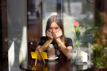 girl drinks coffee and watches video on mobile phone