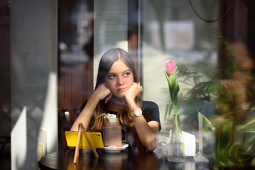 girl drinks coffee and watches video on mobile phone