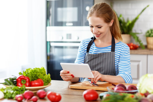 happy woman preparing vegetables in kitchen on prescription with a tablet
