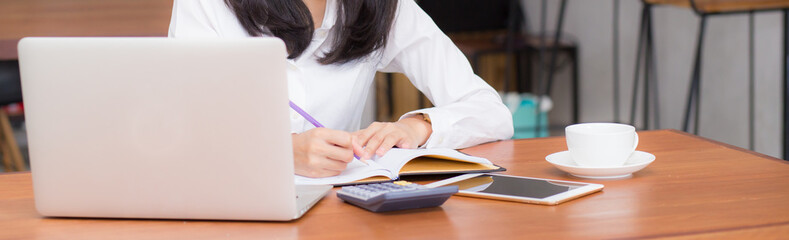 Banner closeup business asian woman writing on notebook on table with laptop, girl work at coffee shop, freelance business concept.