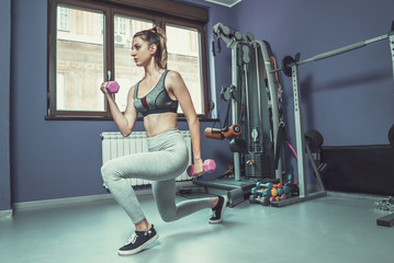 Fototapeta na wymiar Young woman doing exercise at gym, lifting dumbbell weights, kee