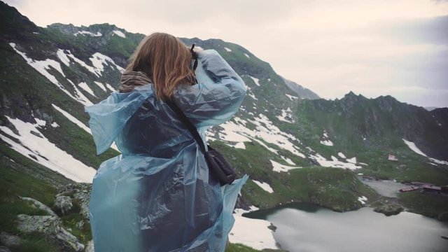 A young woman hiker climbs mountains and photographs landscapes on camera. Transfagarasan, Carpathian mountains in Romania