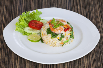 Fried rice with shrimp in a white dish on wood table in thai food style.