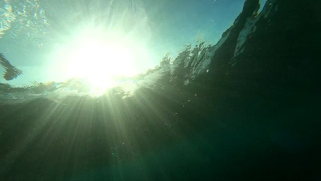 Slow motion underwater view of surfer riding past on green surfing wave
