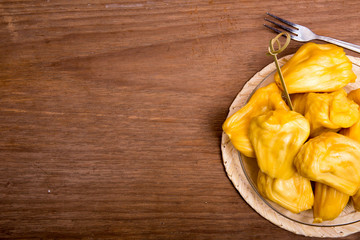 Jack fruit in wooden plate on old wood background.