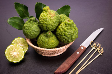 Bergamot, kaffir lime and kaffir lime leaf with basket and knife  on dark background