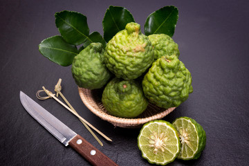 Bergamot, kaffir lime and kaffir lime leaf with basket and knife  on dark background