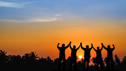 Teams that are willing to share success, stand together, hold hands, look to the sunset the background.Silhouette image