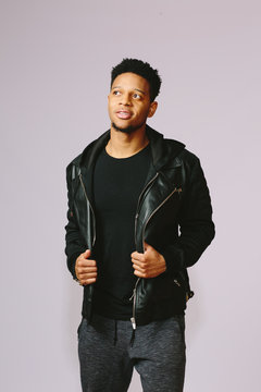 Portrait of a cool guy holding his jacket and looking to side, isolated on grey studio background
