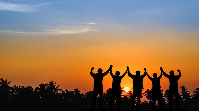 Teams that are willing to share success, stand together, hold hands, look to the sunset the background.Silhouette image