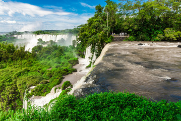 Fototapeta na wymiar Wide angle landscape view of Iguazu falls waterfalls on a sunny day in summer. Photo taken from the Argentinian side.
