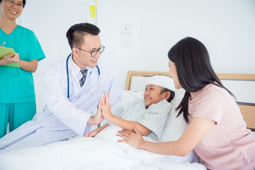 Obraz premium Young asian girl patient smiling and touching hand with doctor while lying on bed