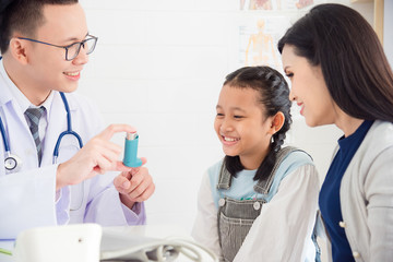 Young asian girl smiling while doctor explain inhaler using method in clinic
