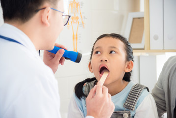 Young asian girl open her mouth for doctor doing oral examination.