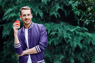 Man in the forest against green tree background with cup of coffee