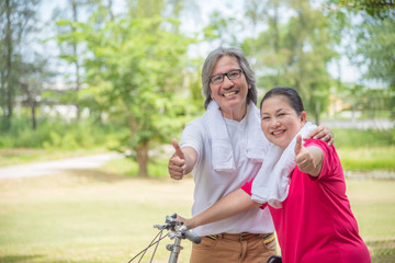 Happy asian retired couple showing thumb up and smile in park