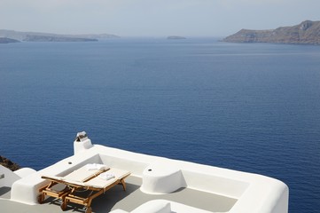 Recliner Chairs for love couples toward Famous stunning view of aegean sea above the volcanic caldera in the village of Oia in Santorini island, Greece