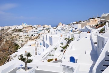 Fototapeta premium Famous stunning view of white architectures and colorful houses above the volcanic caldera in the village of Oia in Santorini island, Greece