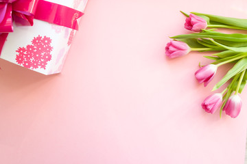 gift with pink ribbon and pink tulips on pink background