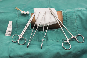 Suture set.clamp, mayo,blade, scissors,forceps,guaze,cotton butt with green cloth on patient. in...