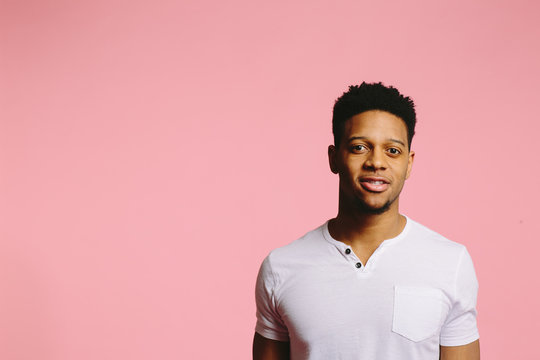 Young man looking at camera with interest, isolated on pink studio background
