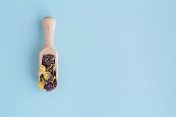 Dried flowers in wooden spoon on blue background.