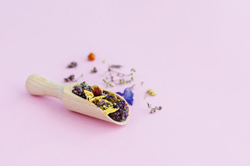 Dried flowers in wooden spoon on pink background.