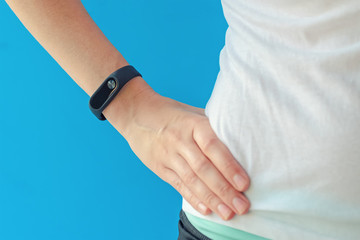 young woman with fitness tracker on hand on blue background