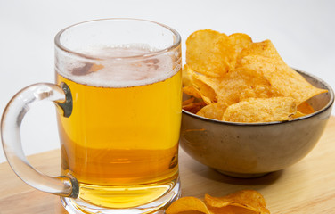 Glass of beer and potato chips on a wooden table

