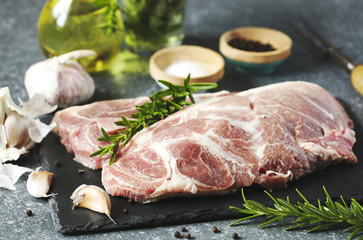 Raw pork meat for grill with ingredients for cooking, dark background.