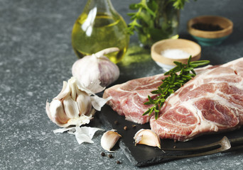 Raw pork meat for grill with ingredients for cooking, dark background.