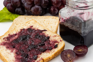 Whole wheat bread with grape jelly spread on a white background.