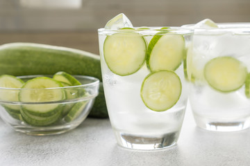 Cold water with cucumber and ice in glass on the table