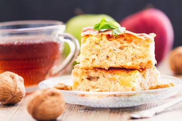 Two pieces of homemade apple pie with tea on a wood table top vintage or rustic background