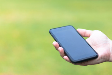 Close-up black smartphone on a man hands on green background with copy space .