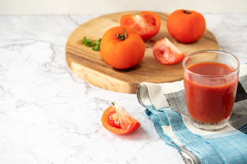 Glass of tomato juice and fresh tomatoes on marble table. copy space