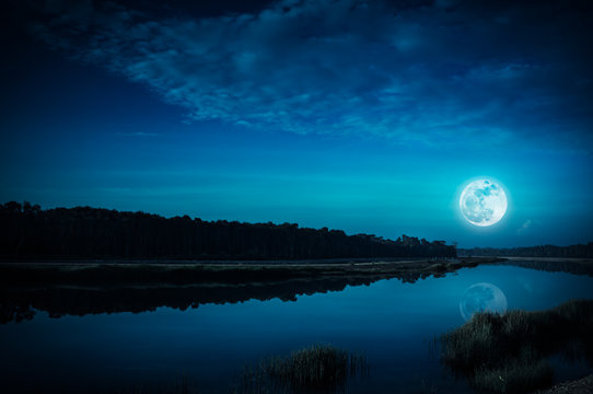 Night sky and bright full moon at riverside. Serenity nature background.