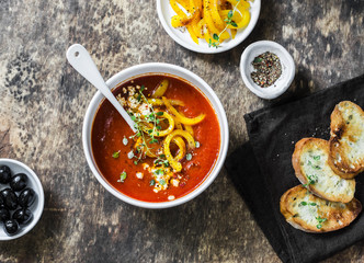 Vegetarian tomato soup with baked yellow sweet pepper on wooden background, top view
