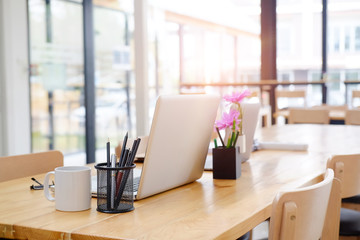 Workplace business office with laptop computer, mug of coffee and pencil jar on wooden table.