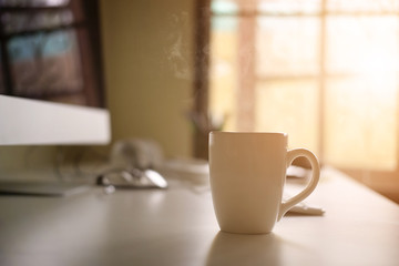 Mug of coffee on office workplace with morning coffee concept.