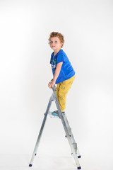 Handsome boy with long curly hair standing on the stepladder