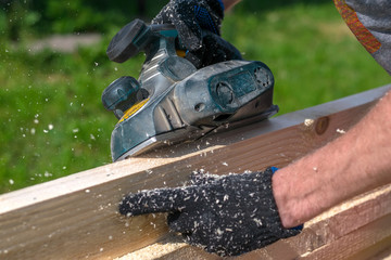 man planing boards with electric tools, chips flying in all directions. Construction, wood processing	