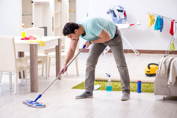 Young attractive man husband doing mopping at home