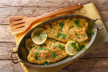 Delicious fish: baked trout fillets with garlic buttery herb sauce, lemon and parsley close-up in a copper pan. horizontal top view