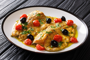 Italian fillet of trout fish with garlic lemon  sauce, tomatoes, parsley and olives close-up on a plate. horizontal