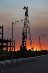 Construction crane at job site during sunset