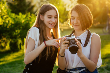 two female friends in the park photographing on a professional camera . photo shoot photosession in...