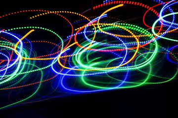 Blur colourful Abstract background of glowing stripes of streaks of light bands in a form of several lines on black background. Long exposure